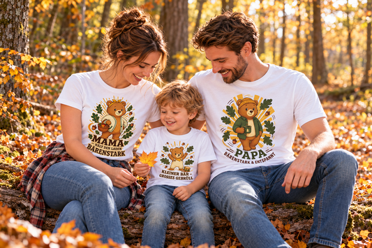 Familie mit Kind trägt aufeinander abgestimmte Waldzauber-Shirts mit Mama-, Papa- und kleinem Bärenmotiv bei einem Ausflug im Herbstwald.